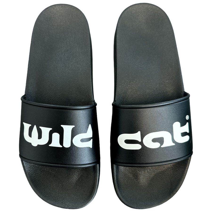 Schwarze Wildcat Sandalen aus PVC mit weißem Logo auf weißem Hintergrund