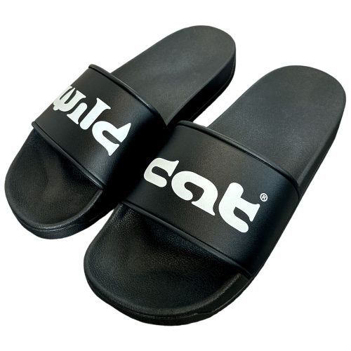 Schwarze PVC-Slides mit weißem Wildcat-Logo auf neutralem Hintergrund