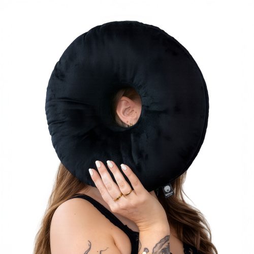 Rundes schwarzes Kissen aus Polyester mit Ohröffnung, von einer Person gehalten, auf weißem Hintergrund