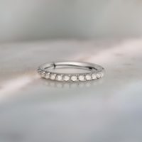 Silberner Piercing-Ring mit Perlenverzierung auf grauem Hintergrund