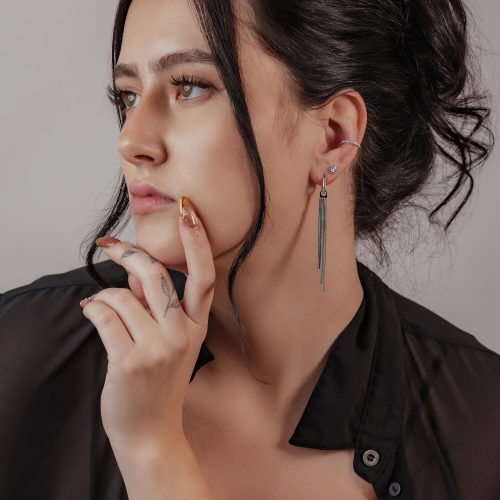 Frau mit elegantem Pearl Clicker Piercing in Silber am Ohr, schwarzes Haar