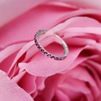 Silberner Clicker-Ring mit roten Kristallen auf rosa Blütenblättern