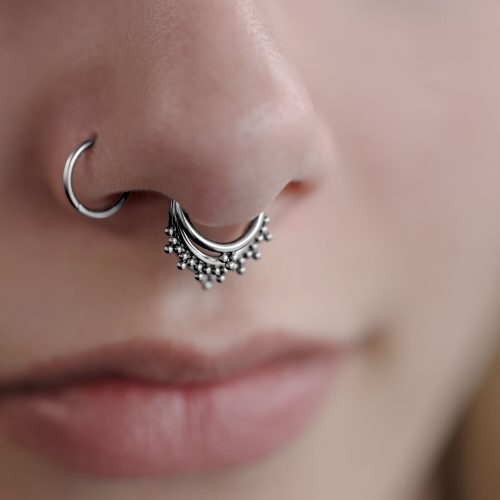 Nahaufnahme eines silbernen Triple Oriental Clickers im Septum eines Gesichts