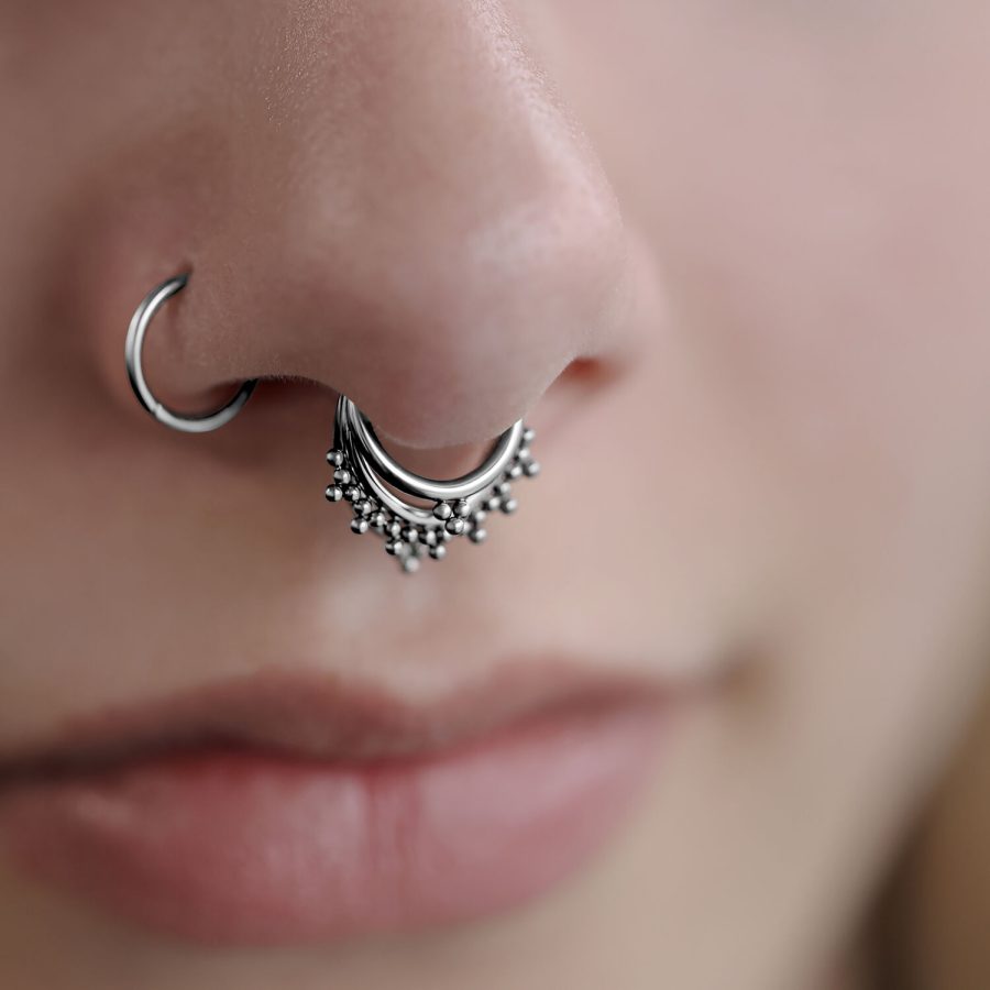 Nahaufnahme eines silbernen Triple Oriental Clickers im Septum eines Gesichts