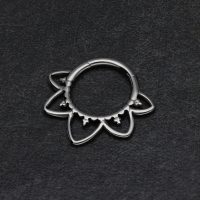 Schwarzer Septum Clicker in Blütenform auf dunklem Hintergrund