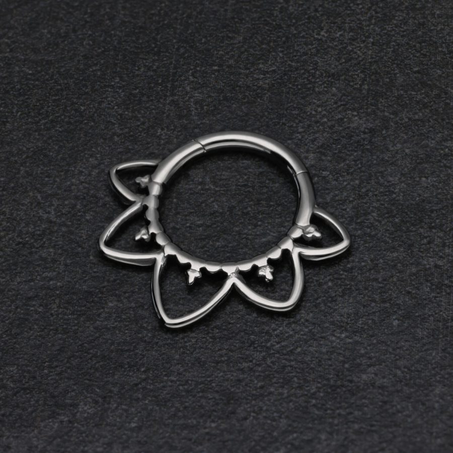Schwarzer Septum Clicker in Blütenform auf dunklem Hintergrund