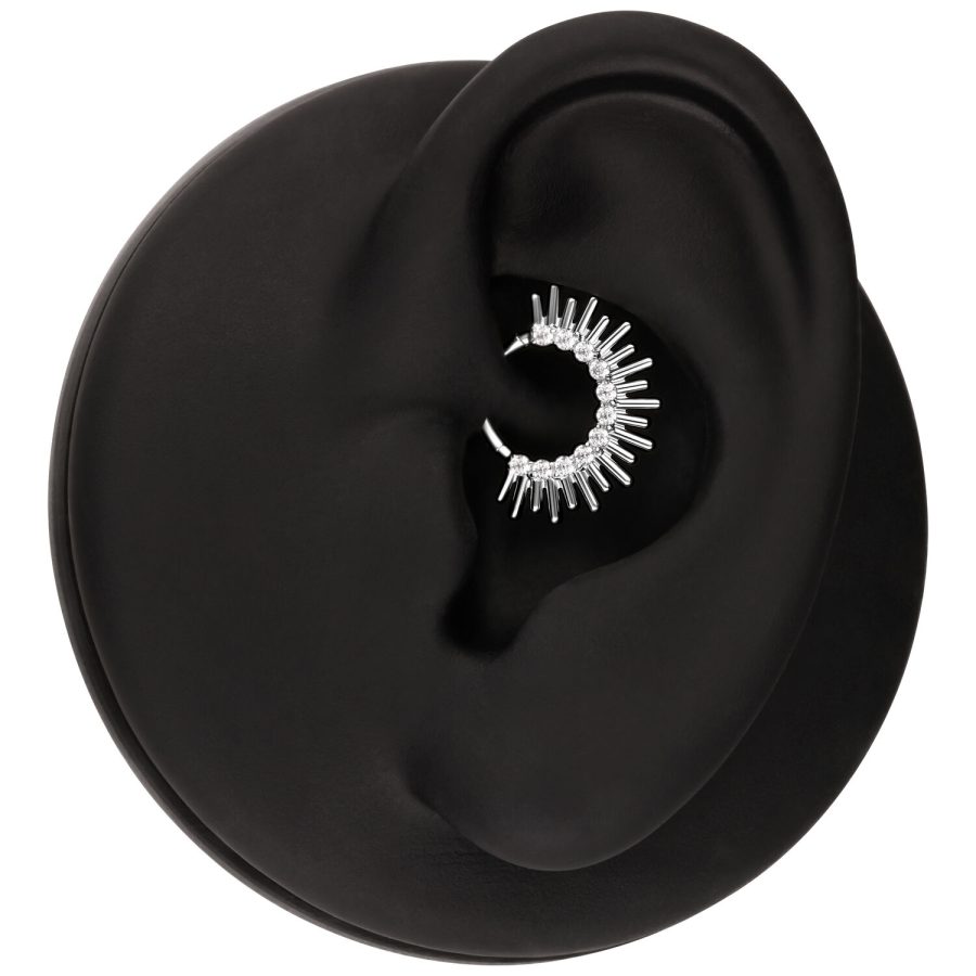 Silberner Septum Clicker in Sonnenstrahlenform in einem schwarzen Ohr auf weißem Hintergrund