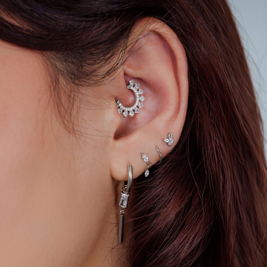 Ohr mit mehreren Piercings, darunter ein silberner Kristall Halo Septum Clicker in der Ohrmuschel.