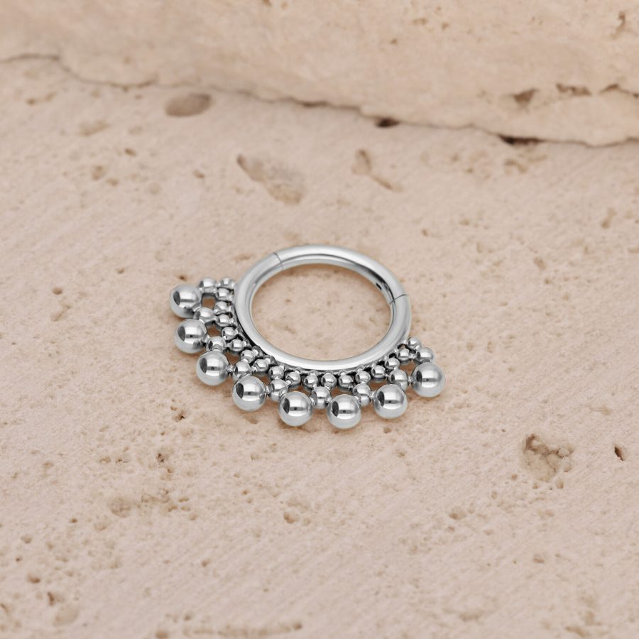 Silberner Septum Clicker mit kleinen Kugeln auf einem strukturierten Steinuntergrund