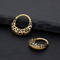 Zwei goldene Septum Clicker mit Leopardenmuster auf schwarzem Hintergrund