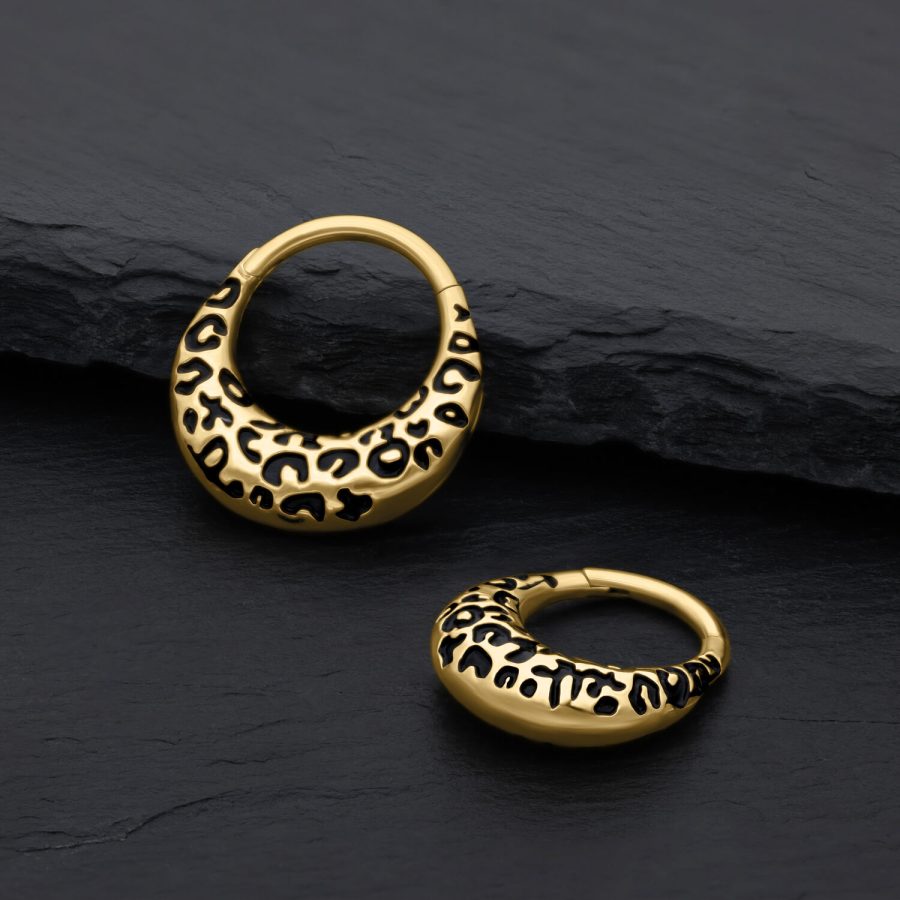 Zwei goldene Septum Clicker mit Leopardenmuster auf schwarzem Hintergrund