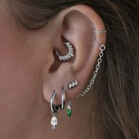 Silberner Piercing Aufsatz aus Titan am Ohr mit mehreren Ohrringen und Kette