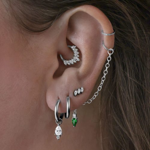 Silberner Piercing Aufsatz aus Titan am Ohr mit mehreren Ohrringen und Kette