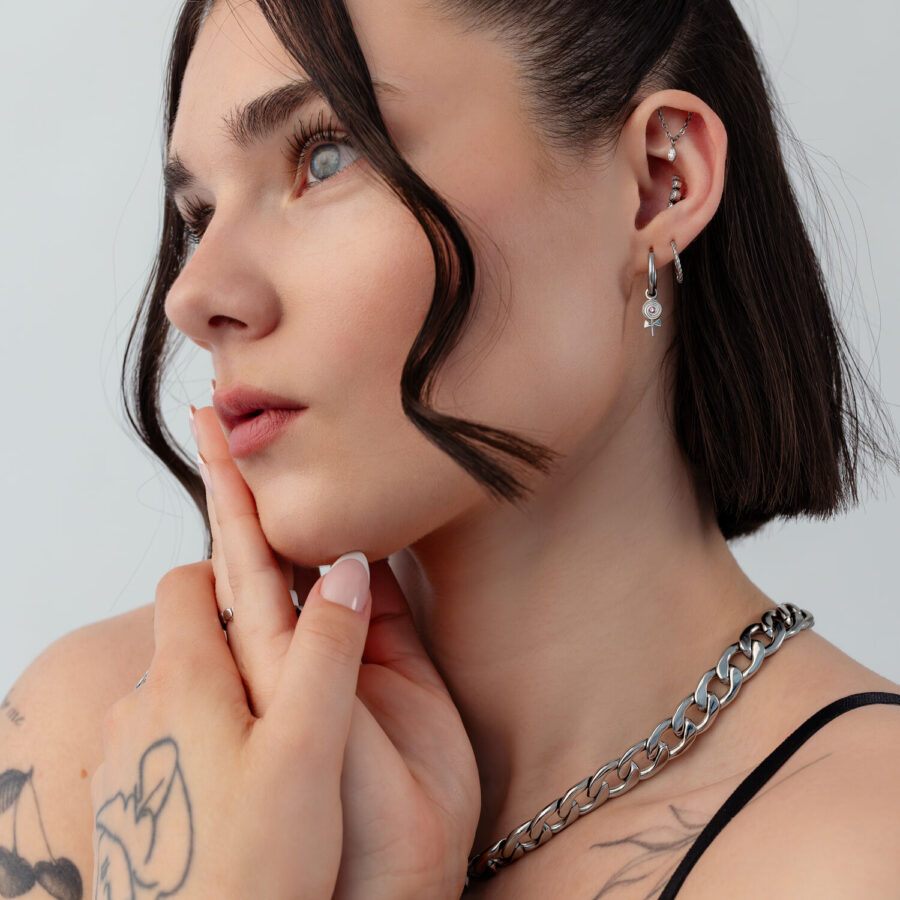 Frau mit Mini Lollipop Creolen, kurze Haare, Tattoos, weißer Hintergrund