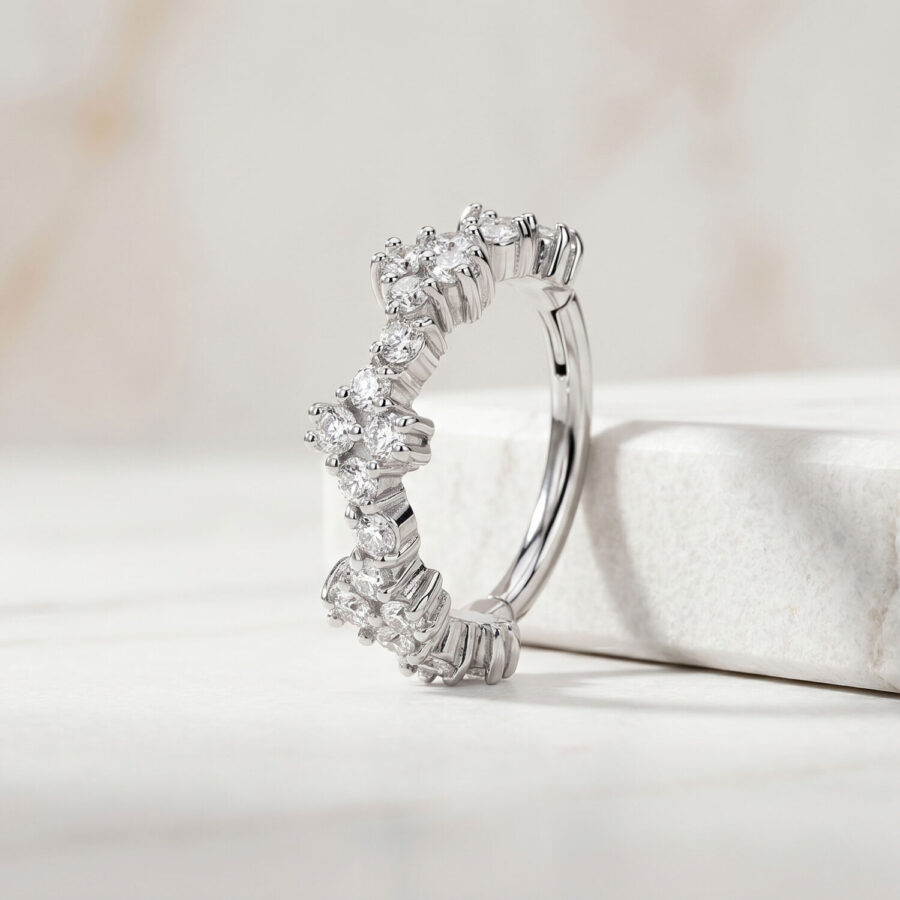 Silberner Piercingring mit klaren Kristallen auf einem weißen Marmorhintergrund