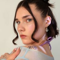 Frau mit kurzem dunklem Haar und Sonnenstrahlen-Piercing-Aufsatz am Ohr