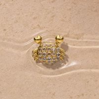 Goldener Krabbenaufsatz mit Strasssteinen auf sandigem Hintergrund