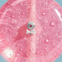 Silberner Lollipop-Aufsatz mit pinkem Stein auf glitzerndem pinken Hintergrund