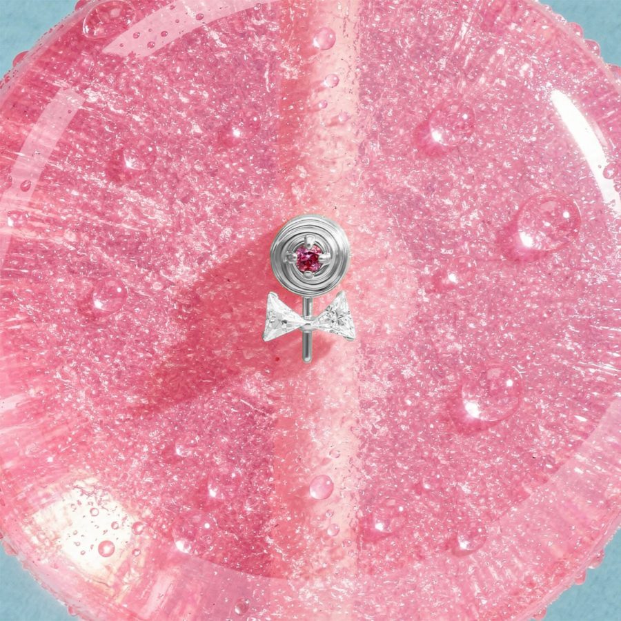 Silberner Lollipop-Aufsatz mit pinkem Stein auf glitzerndem pinken Hintergrund