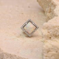 Quadratischer synthetischer Opal in silbernem Rahmen auf beigem Stein