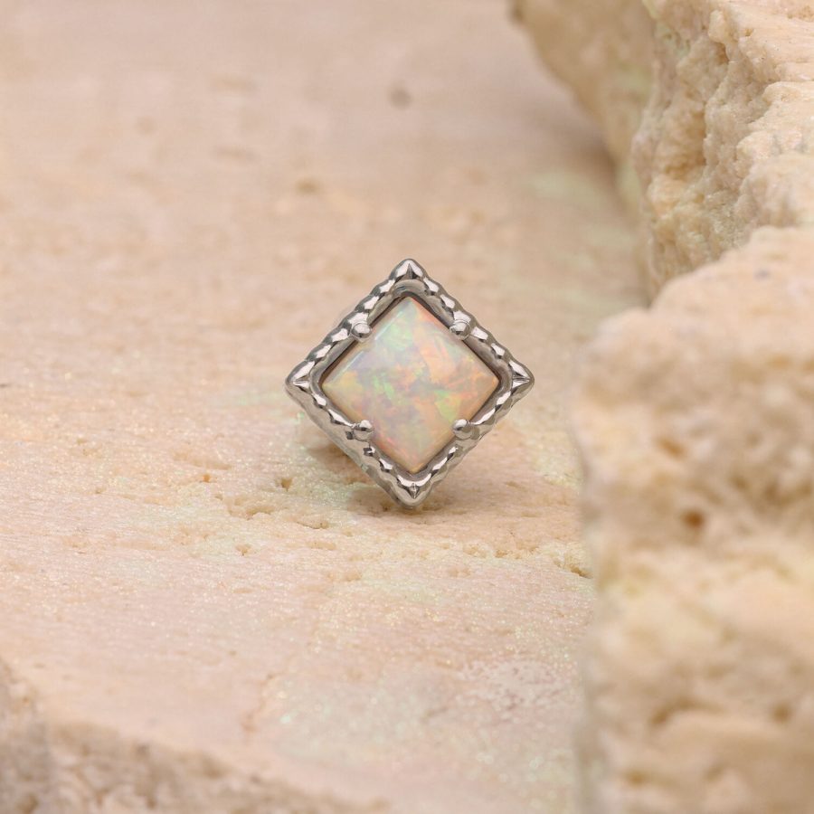 Quadratischer synthetischer Opal in silbernem Rahmen auf beigem Stein