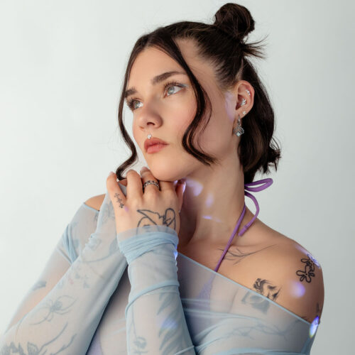 Frau mit blauen Mesh-Top und Tattoo-Muster auf weißem Hintergrund