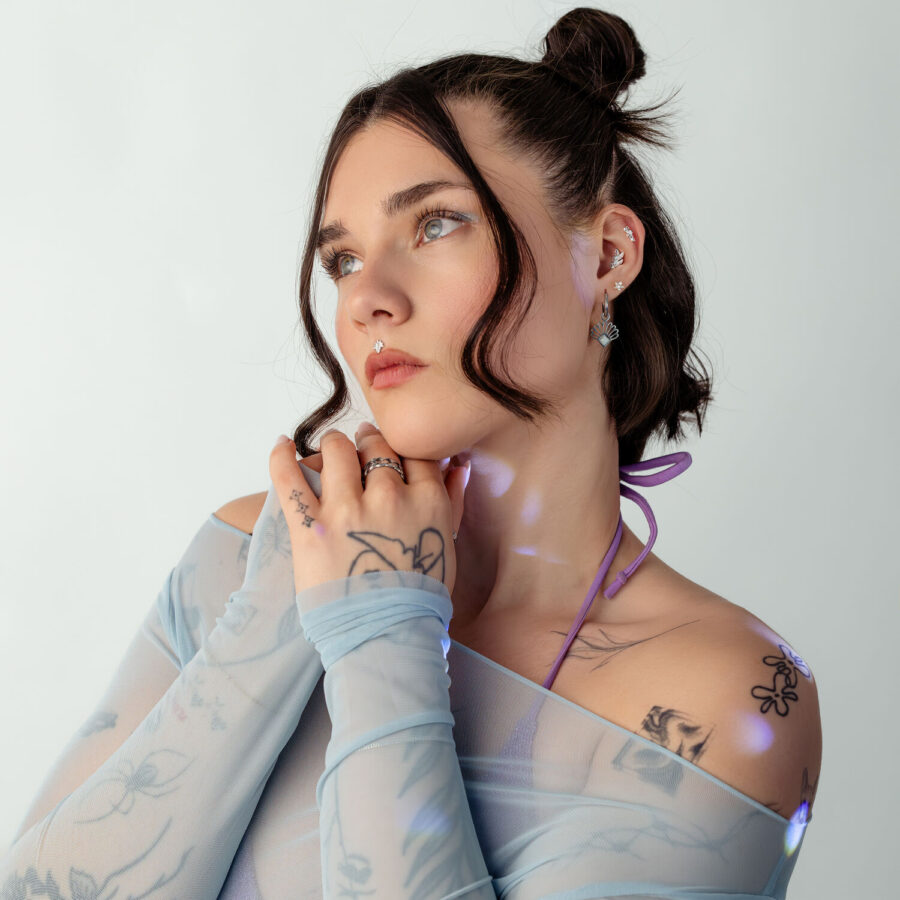 Frau mit blauen Mesh-Top und Tattoo-Muster auf weißem Hintergrund