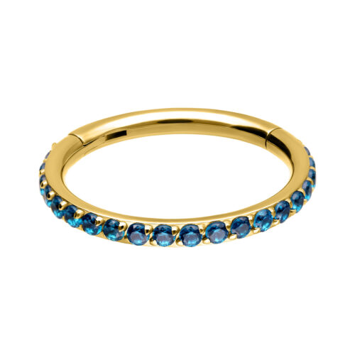 Goldener Piercing Clicker mit türkisfarbenen Kristallen, rundum angeordnet auf weißem Hintergrund.