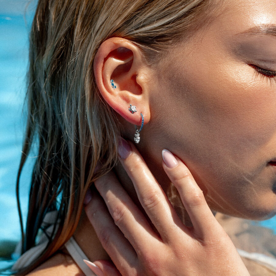 Frau mit mehreren Ohrpiercings, darunter ein türkisfarbener Kristall Clicker, am Pool