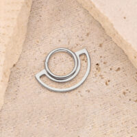 Silberner Ring Clicker auf beigem Steinuntergrund, kreisförmiges Design