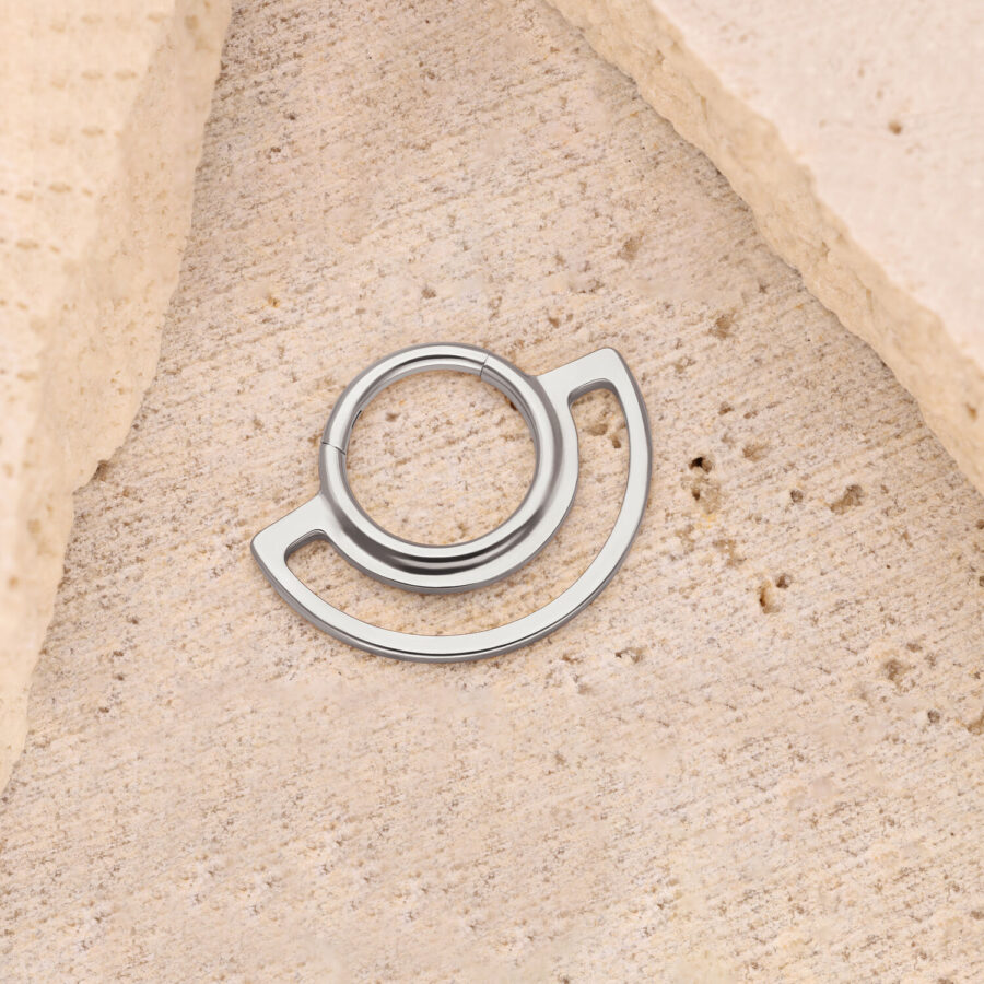 Silberner Ring Clicker auf beigem Steinuntergrund, kreisförmiges Design