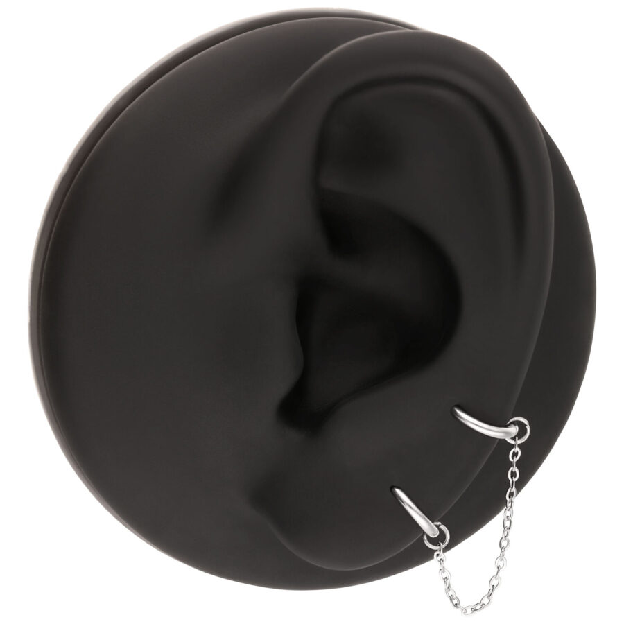 Schwarzes Ohrmodell mit silberner Piercingkette, die zwei Piercings verbindet